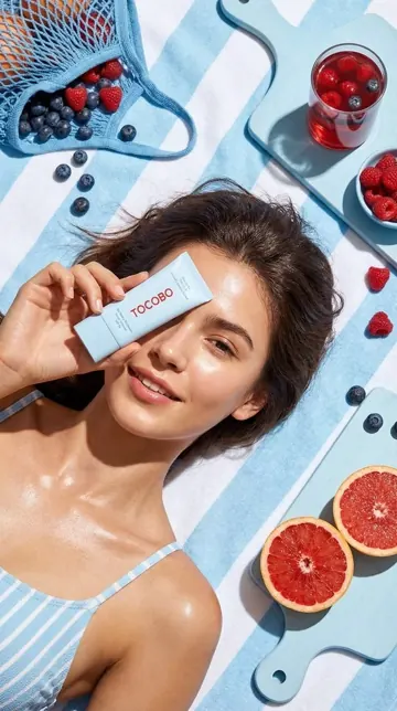 Werbeanzeige für Hautpflege: Anwendung am Gesicht, daneben Früchte als Flatlay
